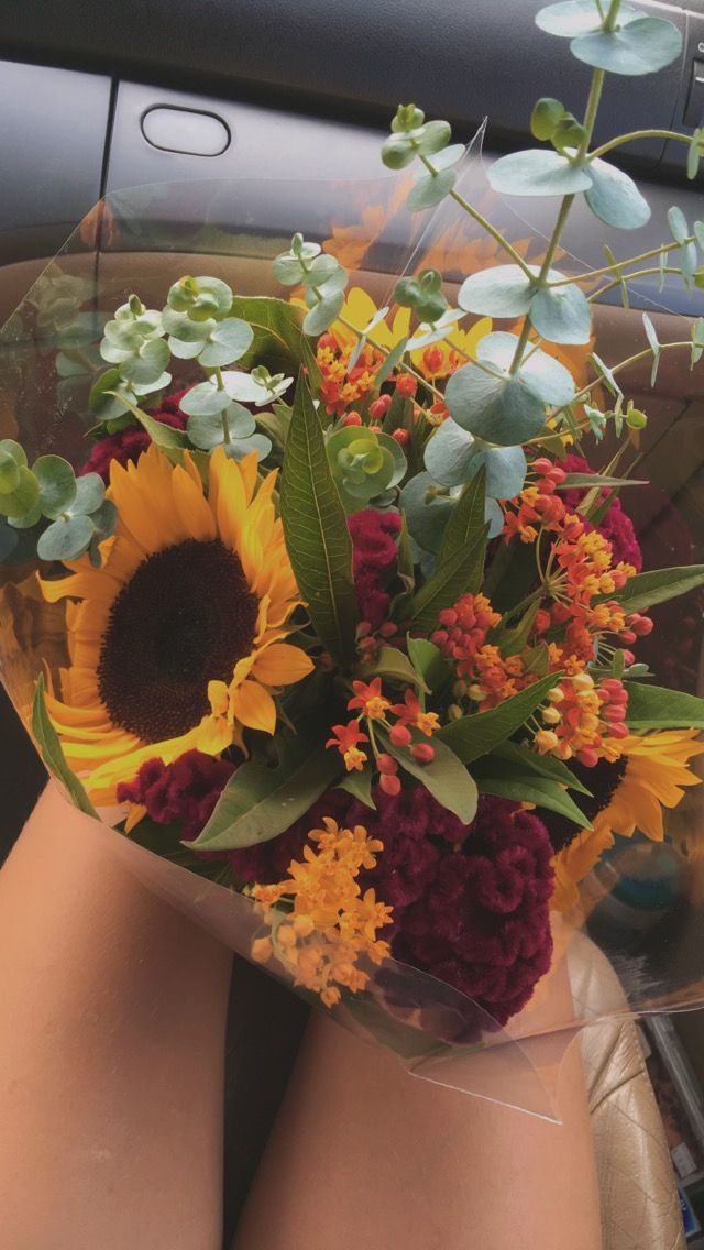 a woman's legs are covered with flowers and greenery in the back seat of a car