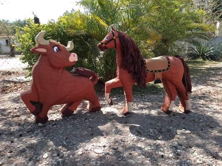 two wooden horses are standing in the dirt