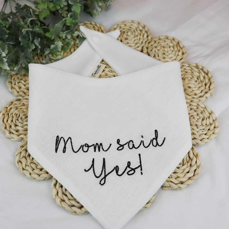 a white bandana with the words mom said yes on it sitting next to a plant