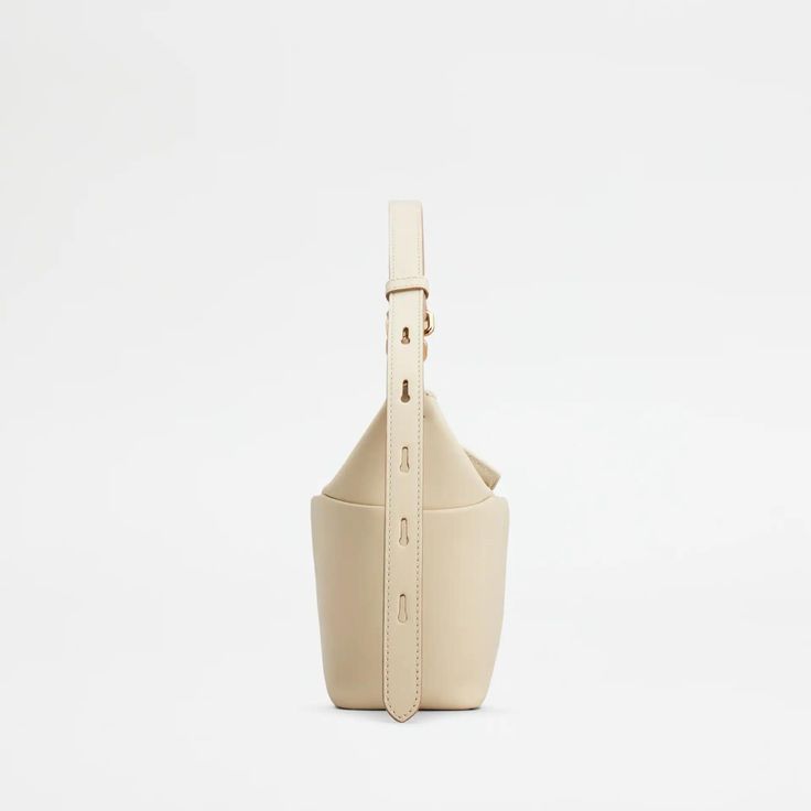 Elevate your style with the T-Box Mini Bag in Beige. Inspired by Japanese origami, this boxy bag features a T Timeless turn-lock buckle and adjustable handle. Crafted in soft calfskin leather, it adds a contemporary touch to any outfit. A must-have for fashion-forward individuals. Chic Leather Bucket Bag With Magnetic Closure, Modern Cream Rectangular Bucket Bag, Formal Cream Leather Bucket Bag, Top Handle Leather Bucket Bag With Magnetic Closure, Leather Bucket Bag With Top Handle And Magnetic Closure, Modern Cream Bucket Bag With Detachable Strap, Cream Leather Bucket Bag With Top Carry Handle, Cream Leather Bucket Bag With Top Handle, Formal Bucket Box Bag With Top Carry Handle