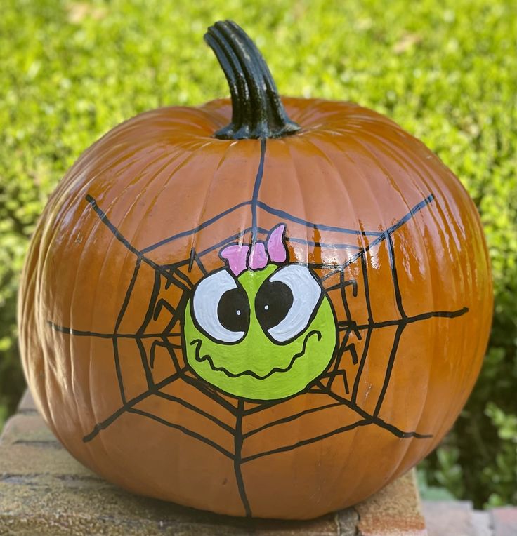 a pumpkin decorated with an image of a spider web on it's face and eyes