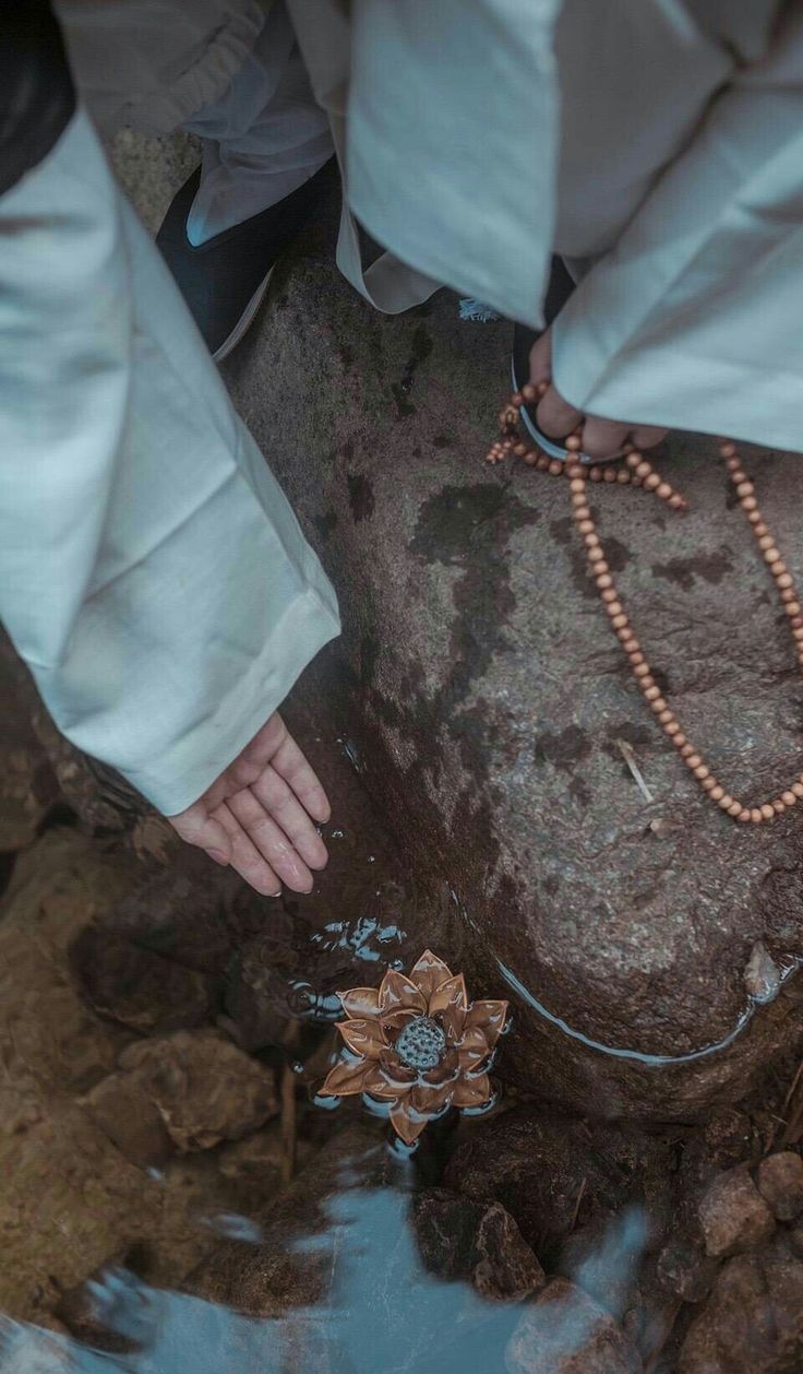 a person standing on top of a rock next to a body of water with a rosary