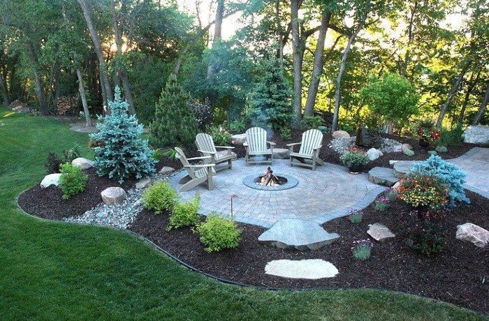 a fire pit surrounded by lawn chairs and trees