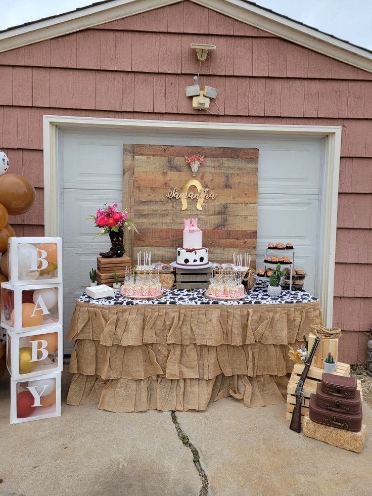 a table topped with cake and desserts in front of a garage door at a birthday party