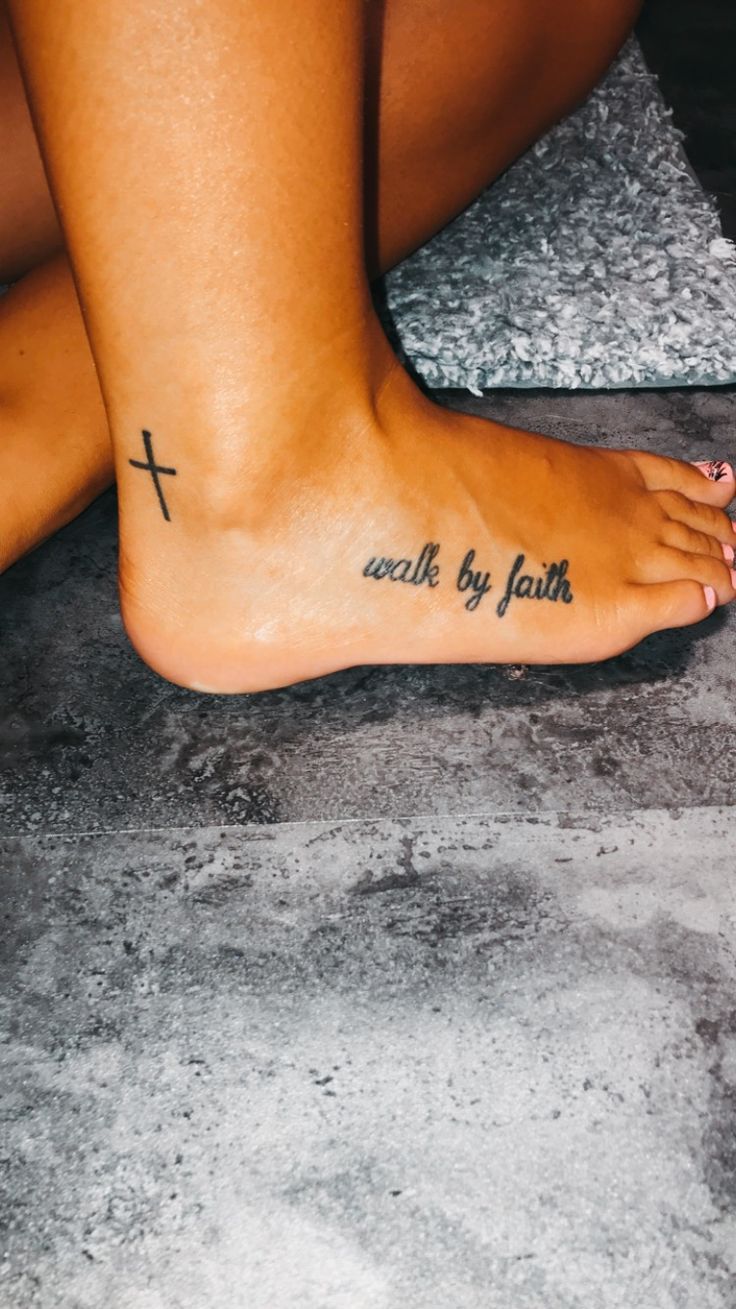 a woman's foot with a cross tattooed on the bottom and words below it