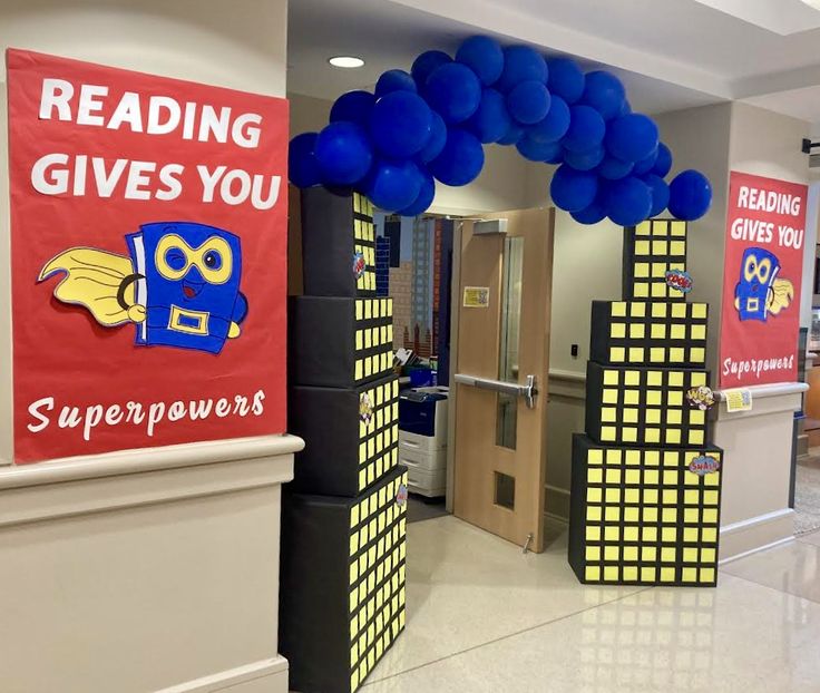 an entrance to a library decorated with blue balloons and reading gives you super powers sign