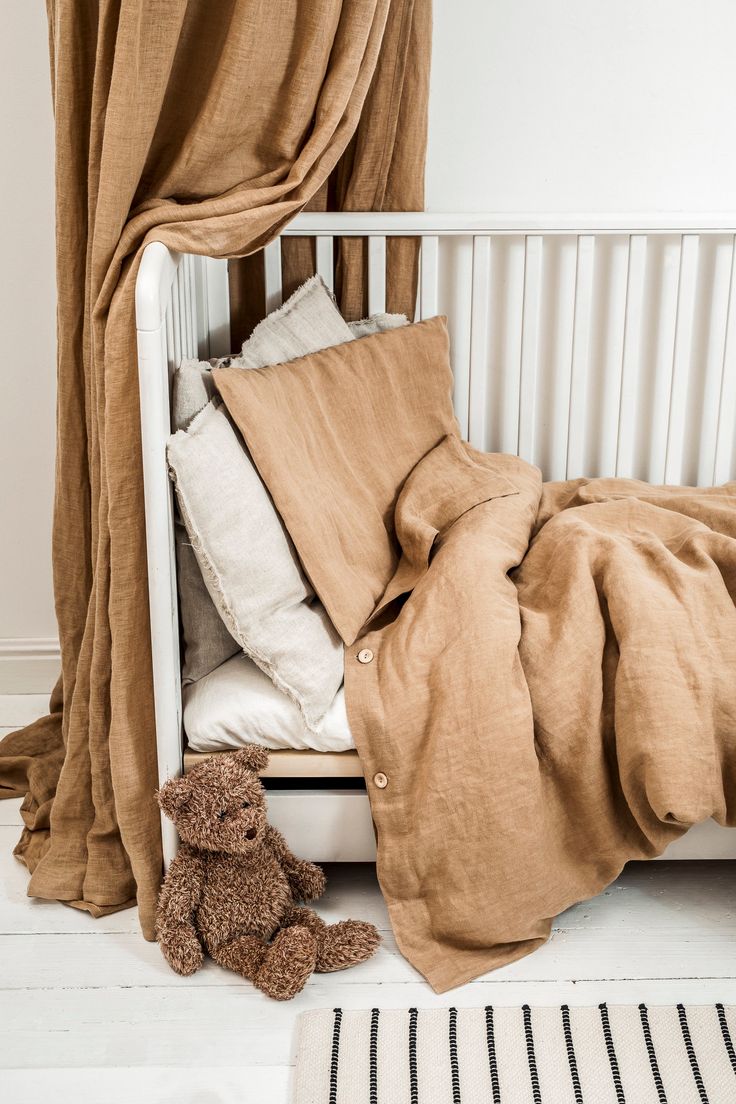 a teddy bear sitting under a blanket on top of a bed