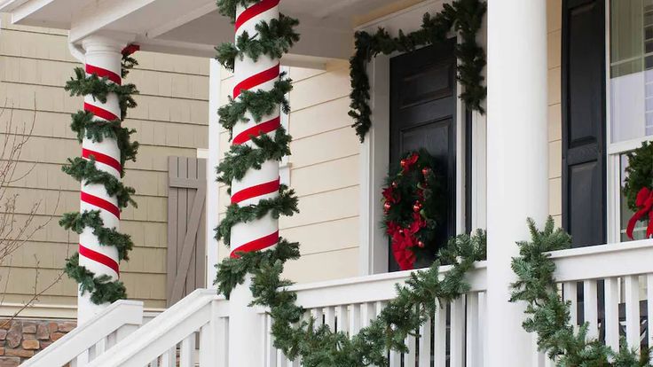 two christmas wreaths on the front porch of a house decorated with candy canes