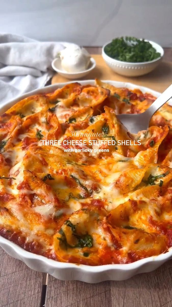 a pizza with cheese and spinach in a white casserole dish on a wooden table