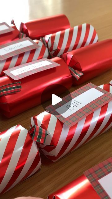 red and white wrapped gift boxes on a wooden table with tags attached to the sides