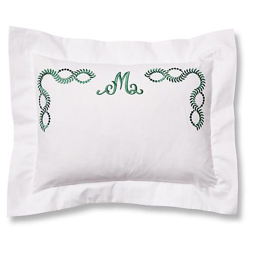 a white pillow with green embroidered monogramming on the front and back of it