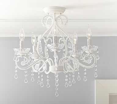 a white chandelier hanging from the ceiling in a room with gray walls and furniture