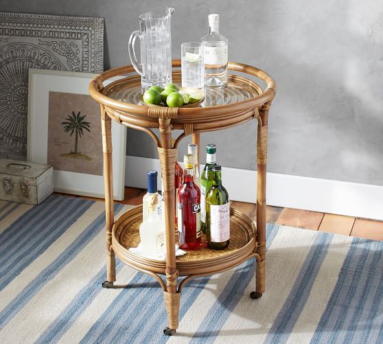 a wicker table with drinks and bottles on it in a room next to a striped rug