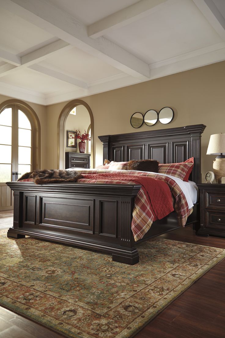 a large bed sitting on top of a wooden floor next to a dresser and mirror