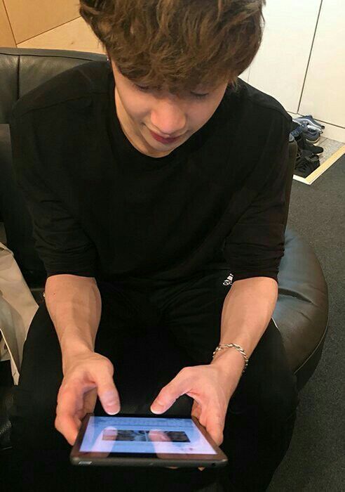 a young man sitting in a chair holding an electronic device with his hands on it