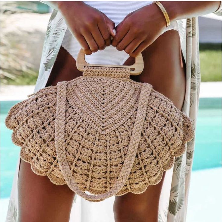 a woman holding a straw bag over her shoulder with the bottom part of her body visible