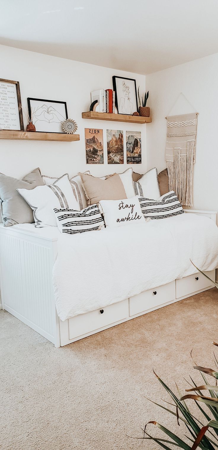 a white bed sitting in the middle of a bedroom next to two shelves with pictures on it