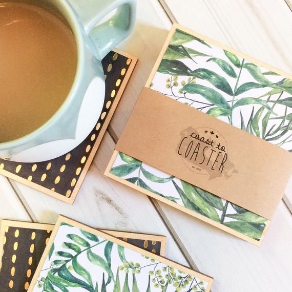 three coasters with green leaves on them next to a cup of coffee