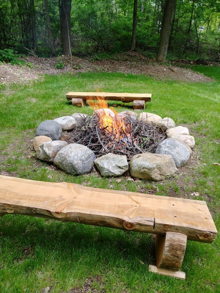 a wooden bench sitting next to a fire pit on top of a lush green field