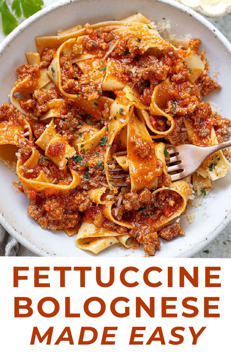 a white bowl filled with pasta and sauce on top of a table next to a fork