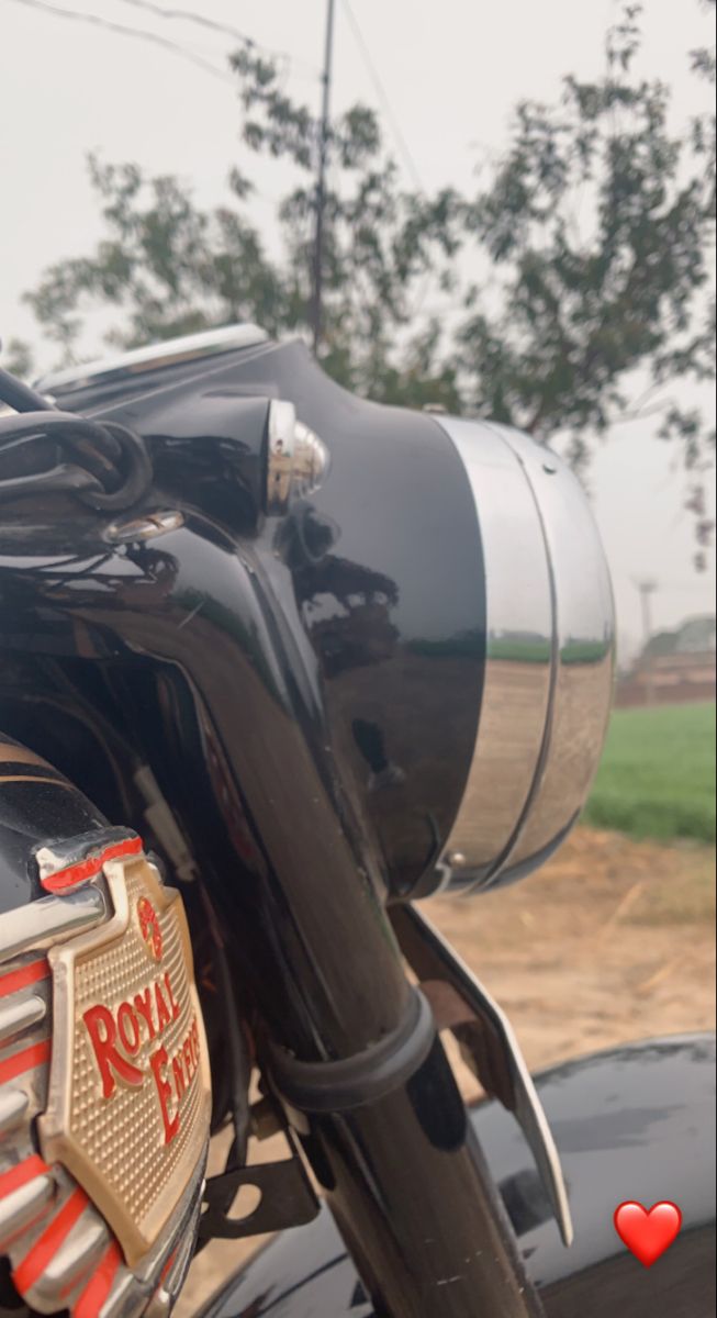 the back end of a black motorcycle parked in front of a field