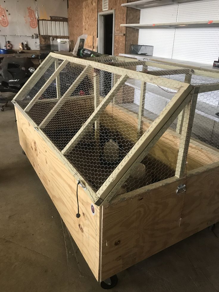 a large wooden box filled with chickens inside of a building