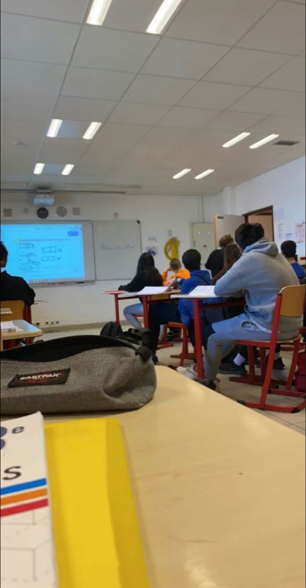 a classroom full of students sitting at desks in front of a projector screen