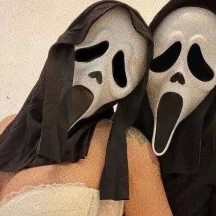 two people with masks covering their faces, one wearing a black dress and the other white