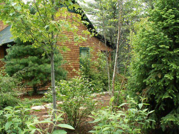 the house is surrounded by trees and plants in front of it's red brick facade