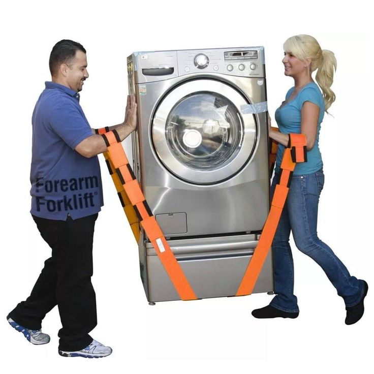 a man and woman are moving a washing machine with orange safety tape on it's sides