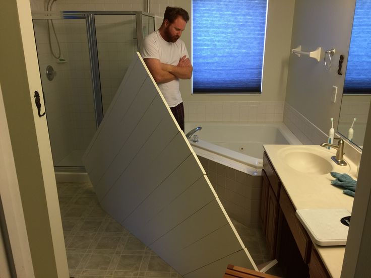 a man standing next to a bath tub in a bathroom