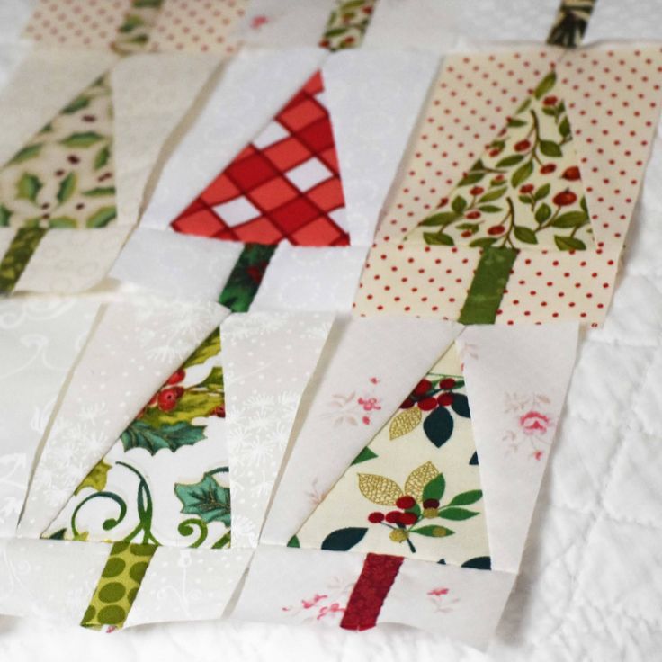 several christmas trees made out of fabric on top of a white tablecloth with red and green trimmings