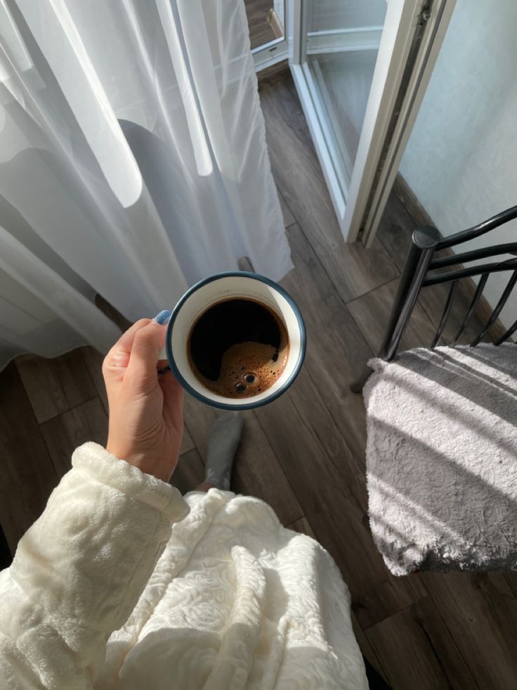 a person holding a cup of coffee in their hand