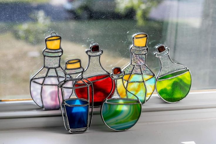 four different colored glass bottles sitting on top of a window sill