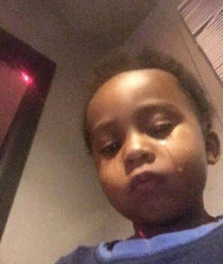 a little boy that is standing in front of a tv with his eyes closed and looking at the camera