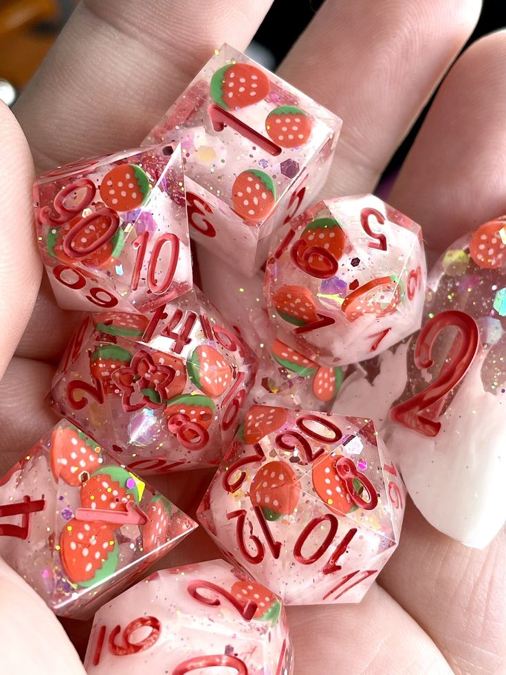 a person holding several dices in their hand with numbers and hearts painted on them