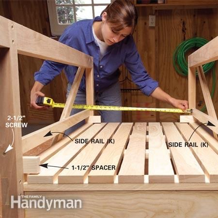 a woman measuring the width of a wooden bed frame with tape measures on it