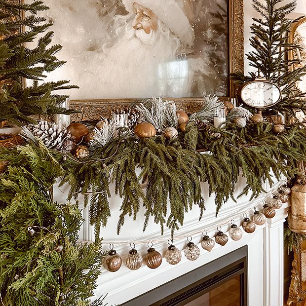 a mantel decorated with christmas decorations and pine cones