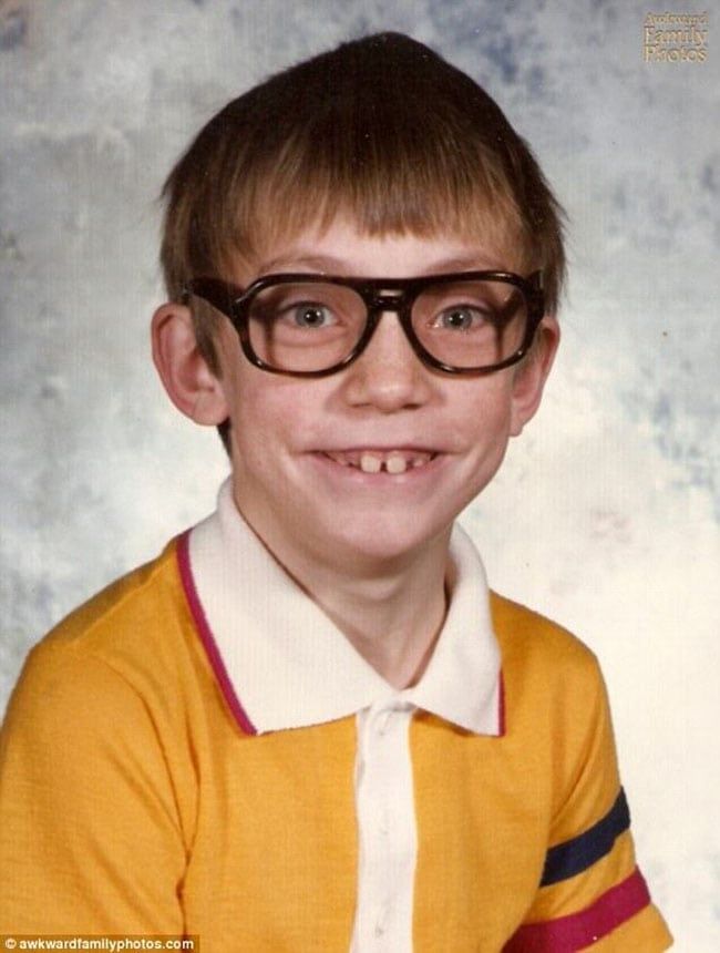 a young boy wearing glasses and smiling at the camera