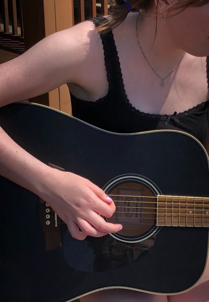 a woman holding a black guitar in her right hand