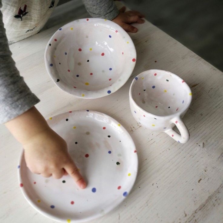 a child is reaching for some polka dot dishes