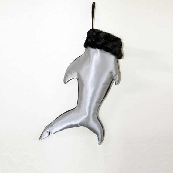 a metal dolphin ornament hanging from a hook on a wall with a black hat