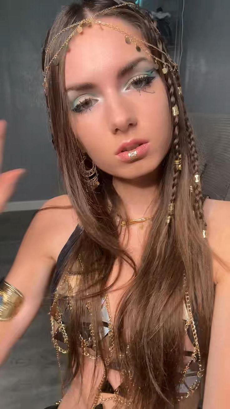 a woman with long brown hair and gold jewelry on her head is posing for the camera