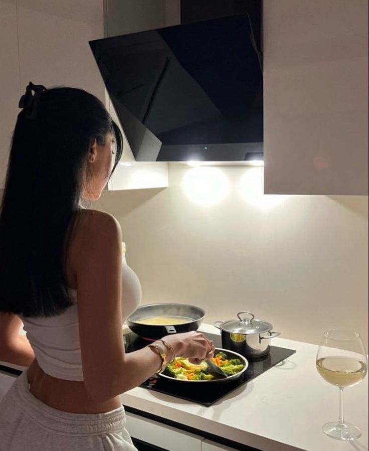 a woman standing in front of a stove top with food on it's burners