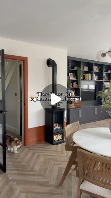 a living room and dining area with a fireplace in the center, wood flooring and white walls