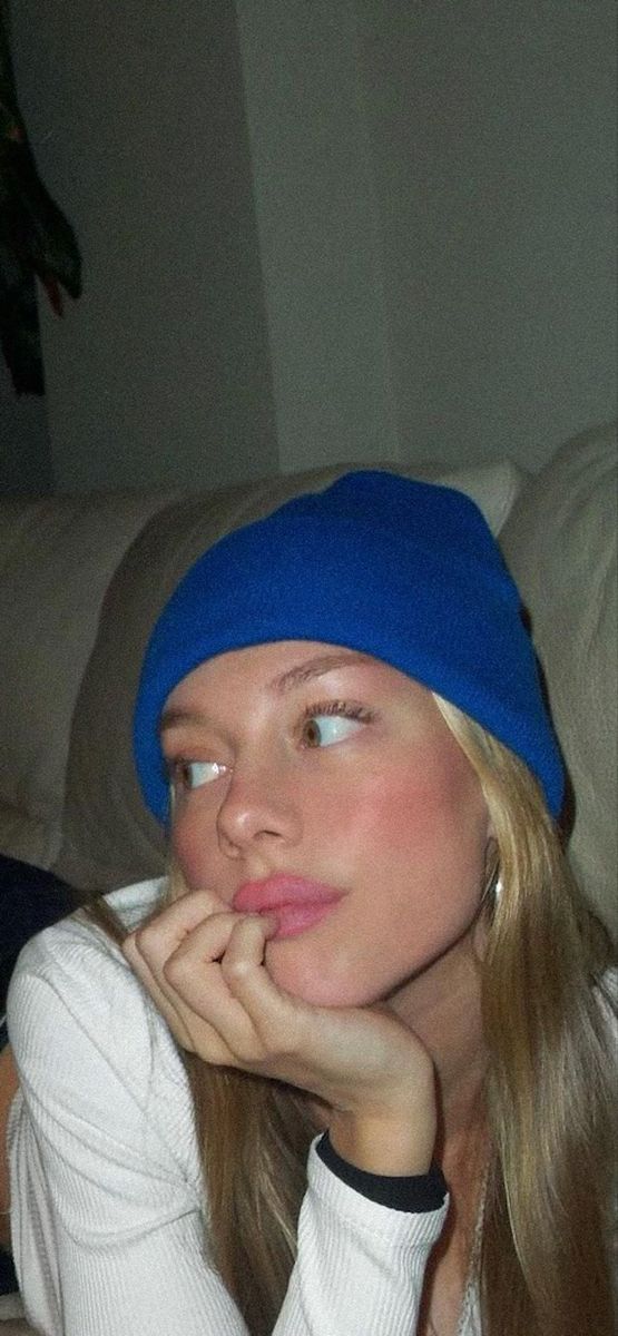 a woman wearing a blue beanie sitting on top of a couch