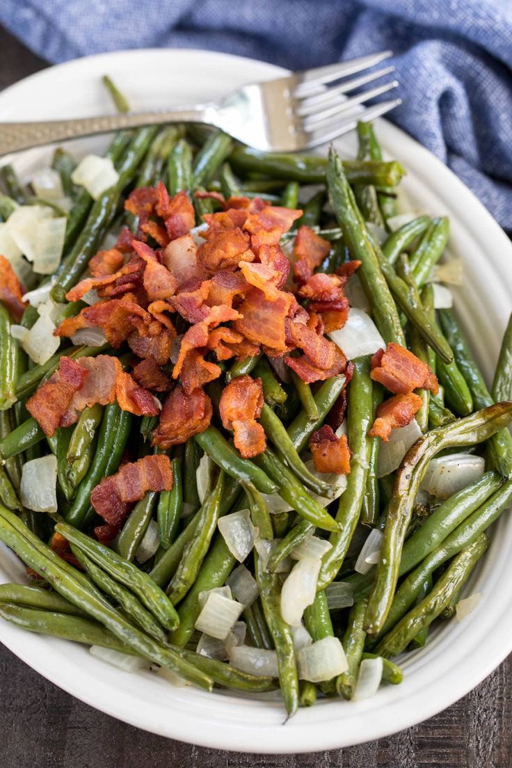 a white bowl filled with green beans and bacon