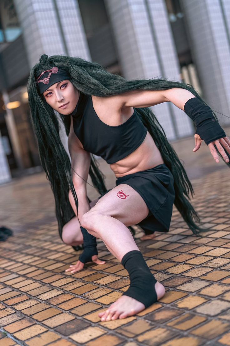 a woman with long black hair and tattoos on her face is posing in front of a building