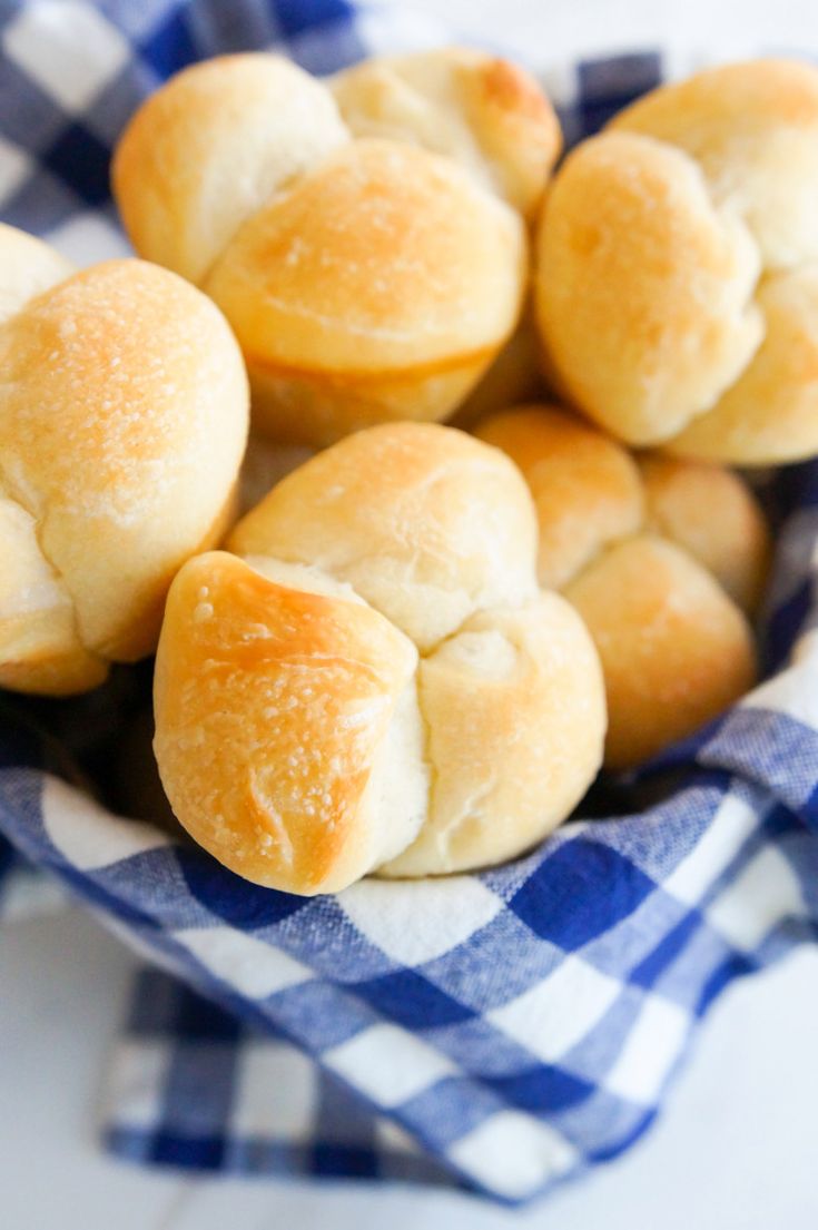 small rolls sitting in a blue and white checkered cloth on top of a table