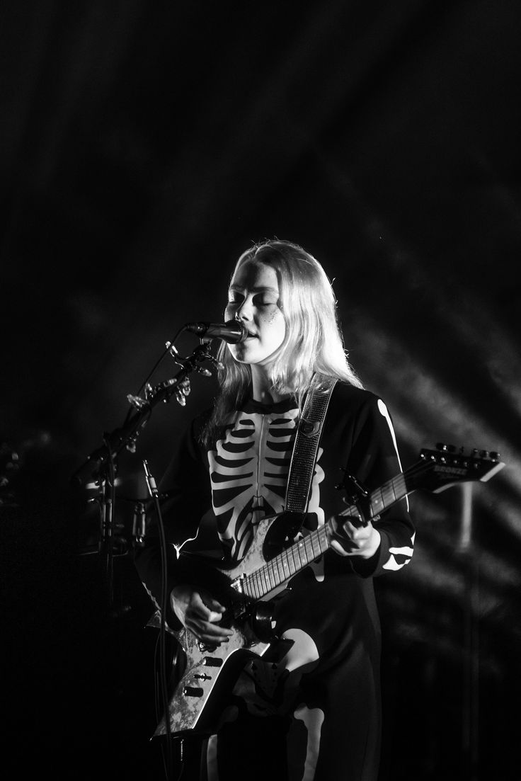 a woman in skeleton costume playing guitar on stage